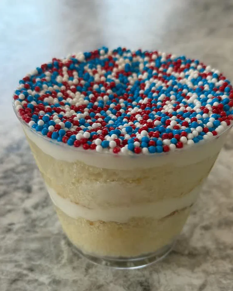 A custom Dot Cake in a clear cup with cream layers and red, white, and blue nonpareils, photographed by The Cookie Cartel NJ.