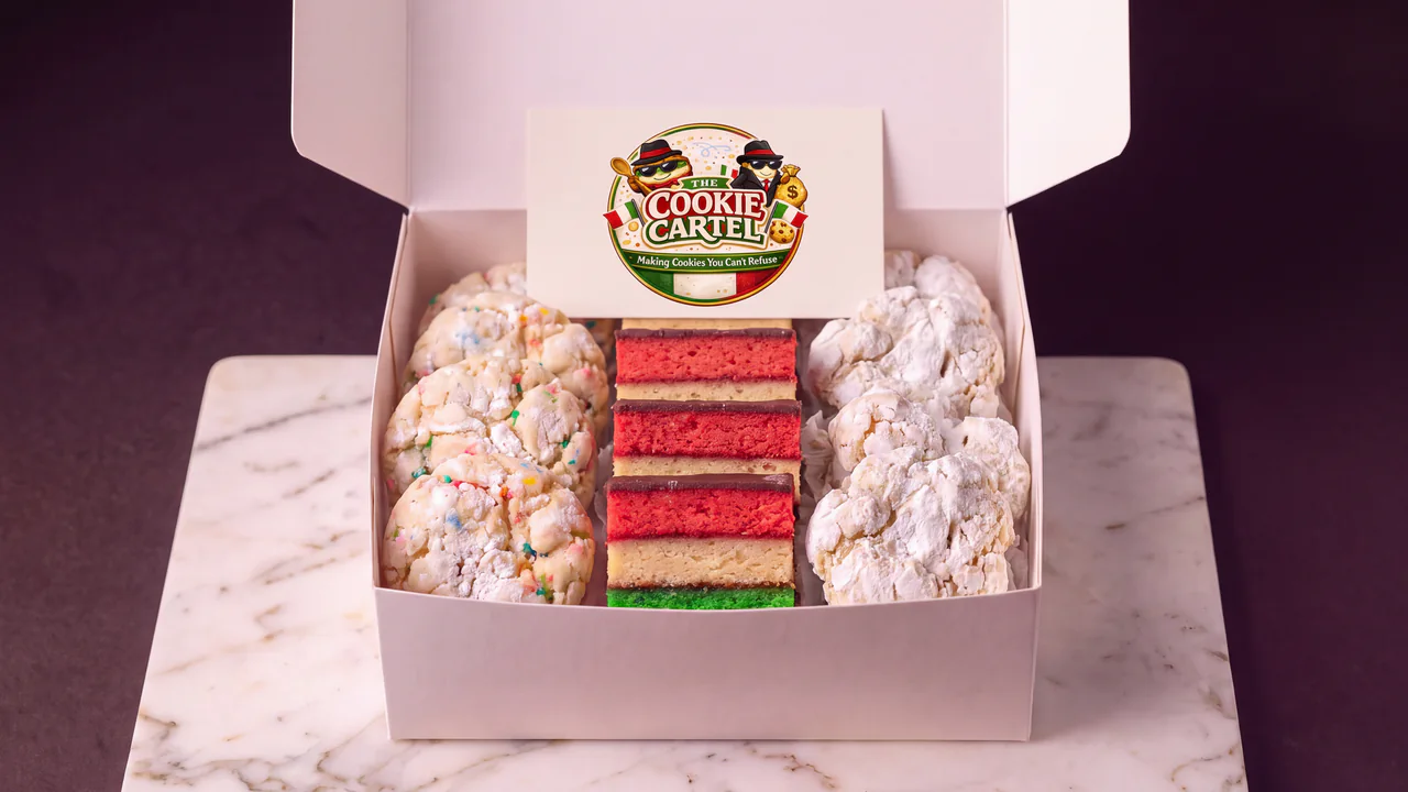 An open Cookie Cartel box of tricolor rainbow cookies between Funfetti and powdered-sugar crinkle cookies.